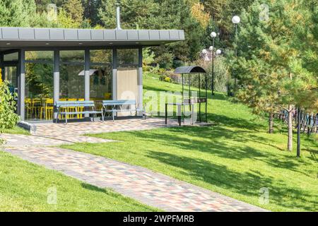 Maison d'hôtes avec murs de verre et zone de barbecue dans la cour à la station d'été. Bâtiment de café avec équipement de barbecue extérieur dans le jardin. Placez-le pour vous reposer Banque D'Images