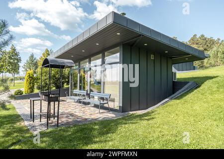 Maison d'hôtes avec murs de verre et zone de barbecue dans la cour à la station d'été. Bâtiment de café avec équipement de barbecue extérieur dans le jardin. Placez-le pour vous reposer Banque D'Images