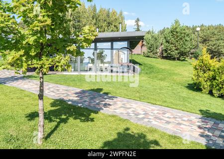 Maison d'hôtes avec murs de verre et zone de barbecue dans la cour à la station d'été. Bâtiment de café avec équipement de barbecue extérieur dans le jardin. Placez-le pour vous reposer Banque D'Images