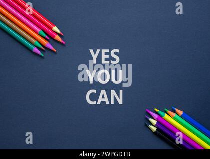Motivation Oui vous pouvez symboliser. Mots conceptuels Oui vous pouvez sur du beau papier noir. Belle table noire fond noir. Crayons de couleur. Affaires Banque D'Images