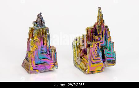 Beaux cristaux de trémie de bismuth cassants colorés avec structure en escalier sur fond blanc. Deux pièces en métal lourd d'élément chimique diamagnétique. Banque D'Images