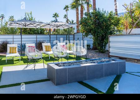 Chaises longues extérieures arrière avec parasols, oreillers colorés et cheminée à Palm Springs, en Californie Banque D'Images