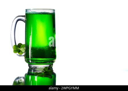 Boisson verte dans un verre clair à côté de trèfles sur une table en verre avec espace de copie à droite. Banque D'Images