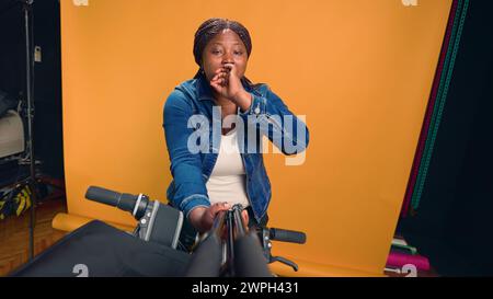 Point de vue du livreur afro-américain utilisant un bâton de selfie et un téléphone pour faire un appel vidéo et mener une conférence vlog en ligne. Femme noire excitée bavardant à la caméra sur le travail de messagerie. Banque D'Images