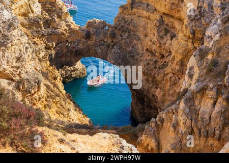 Algarve, Portugal - 14.09.2023 : touristes sur bateau à moteur à l'arc de la cathédrale à Ponta da Piedade, côte de l'Algarve, Lagos, Portugal. Banque D'Images