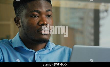 Homme d'affaires afro-américain adulte entrepreneur ethnique s'assoir au bureau à l'intérieur homme employé 30s Manager travaillant avec ordinateur portable de recherche Banque D'Images
