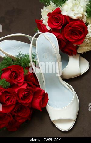 Roses rouges et chaussures de mariée blanc cassé Banque D'Images