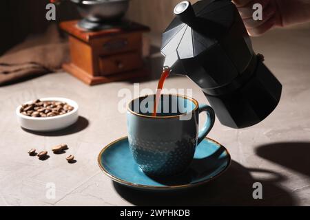 Verser le café aromatique du pot de moka dans la tasse à la table lumineuse, gros plan Banque D'Images