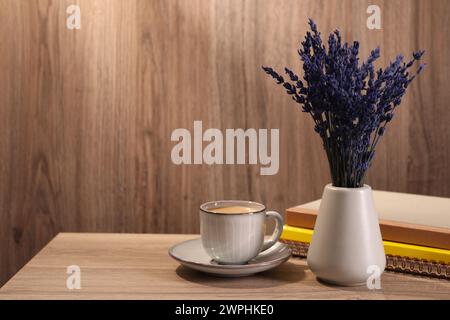 Bouquet de belles fleurs de lavande conservées, cahiers et tasse de café sur une table en bois à l'intérieur, espace pour le texte Banque D'Images