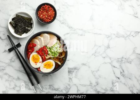 Délicieux ramen dans un bol servi sur une table en marbre blanc, plat avec espace pour le texte. Soupe de nouilles Banque D'Images