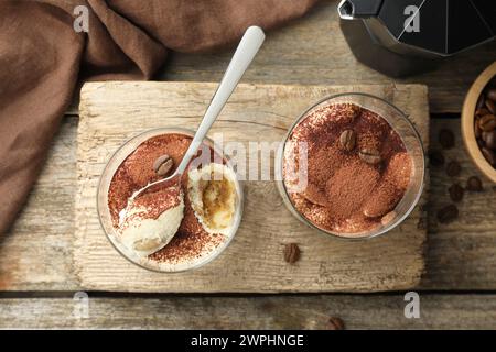 Délicieux tiramisu dans des verres, cuillère et grains de café sur une table en bois, vue de dessus Banque D'Images
