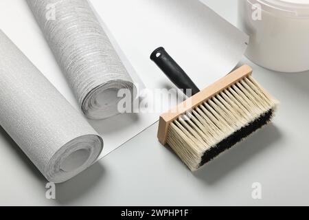 Différents rouleaux de papier peint et brosse sur fond gris clair Banque D'Images