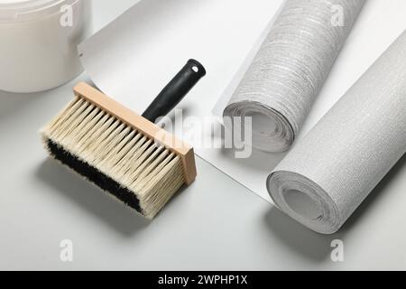 Différents rouleaux de papier peint et brosse sur fond gris clair Banque D'Images