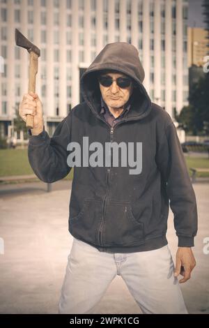 Homme âgé agressif avec hache sous l'influence de médicaments dans le parc Banque D'Images