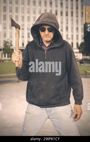 Homme âgé agressif avec hache sous l'influence de médicaments dans le parc Banque D'Images