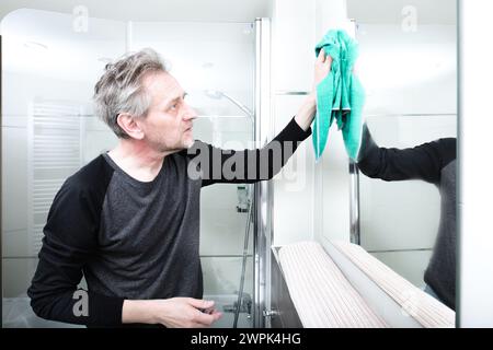 Homme plus âgé nettoyant l'espace de salle de bains dans l'appartement Banque D'Images