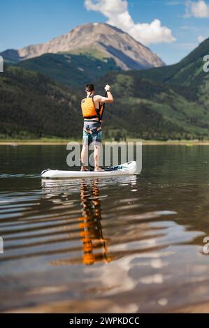 Paddleboarder avec vue sur la montagne profite du calme du lac Banque D'Images