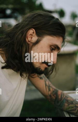 Portrait d'un jeune homme aux longs cheveux bruns et aux yeux foncés. Banque D'Images