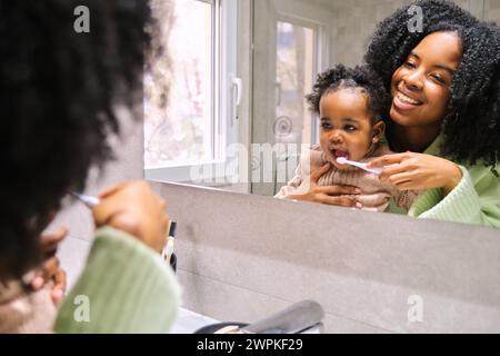 Mère cubaine brossant les dents de sa petite fille dans la salle de bain. Banque D'Images