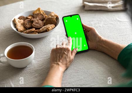 téléphone portable avec écran vert chromakey affichage dans la main de femme âgée Banque D'Images