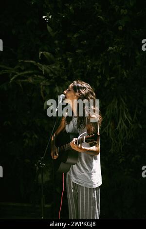 Jeune chanteuse, chante dans un micro et joue de la guitare. Banque D'Images