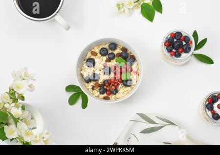 Petit déjeuner végétalien : avoine avec raisins secs et fruits, table décorée de fleurs, vue de dessus. Été ou printemps. Banque D'Images