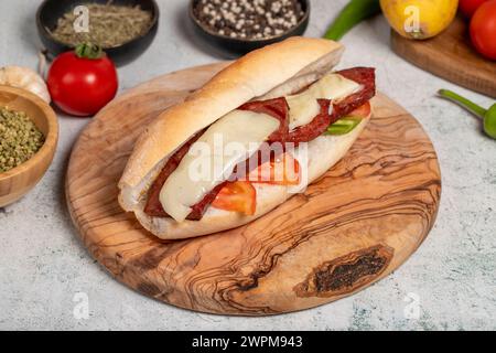 Sandwich au pain turc avec saucisse kashar sur le tableau de présentation. Saucisse dans du pain préparé avec des tomates, des poivrons et des boulettes de viande. Nom local ekmek Banque D'Images