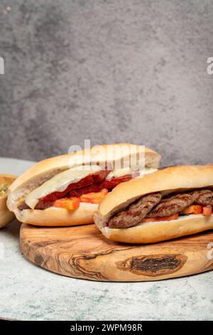 Pain turc avec saucisse kashar et boulettes de viande sur le tableau de présentation. Nom local ekmek arası sucuk ve köfte Banque D'Images
