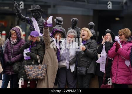 Les militantes pour les femmes contre l'inégalité des pensions de l'État (Waspis) se rassemblent devant la statue de la militante politique Mary Barbour, la femme qui a dirigé les grèves de loyer pendant la première Guerre mondiale, à Govan, Glasgow, pour marquer la Journée internationale de la femme. Date de la photo : vendredi 18 août 2023. Banque D'Images