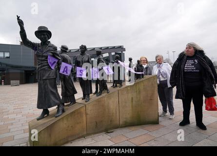 Les militantes pour les femmes contre l'inégalité des pensions de l'État (Waspis) se rassemblent devant la statue de la militante politique Mary Barbour, la femme qui a dirigé les grèves de loyer pendant la première Guerre mondiale, à Govan, Glasgow, pour marquer la Journée internationale de la femme. Date de la photo : vendredi 18 août 2023. Banque D'Images