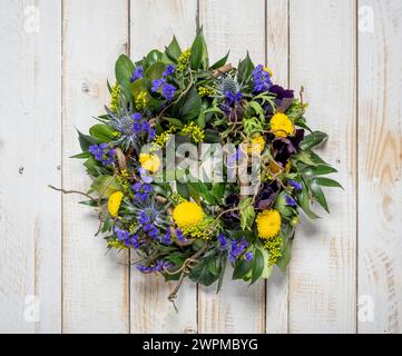 Couronne de printemps de fleurs violettes et jaunes sur un fond rustique en bois blanchi à la chaux Banque D'Images
