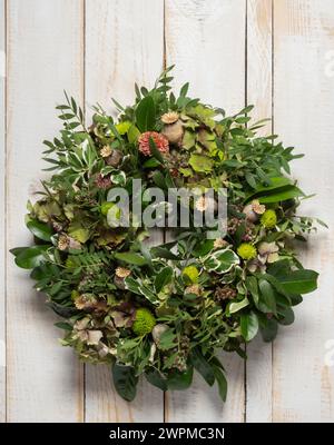 Couronne de porte d'automne composée d'hortensias de couleur bronze, de feuillage et de têtes de graines de pavot sur un fond de bois blanc rustique Banque D'Images