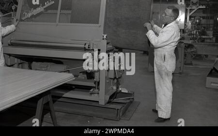 Années 1950, historique, deux ouvriers masculins à la fabrique de papier Camas, WA, USA, prenant une partie d'une machine Hyland 153. Banque D'Images