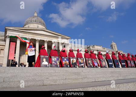 Londres, Royaume-Uni, 8 mars 2024. Des femmes vêtues de servantes racontent des costumes qui défilent dans le centre de Londres à l'occasion de la Journée internationale de la femme pour exiger des améliorations dans les droits et libertés de ceux qui vivent sous le régime islamique en Iran. Des manifestations ont secoué la nation après la mort de la kurde Mahsa Jina Amini en garde à vue. Crédit : onzième heure photographie/Alamy Live News Banque D'Images