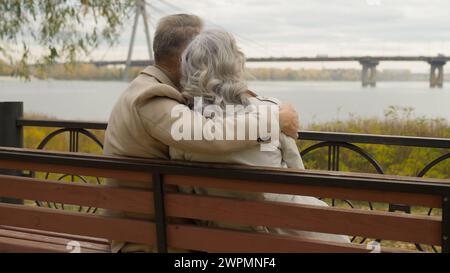 Vue arrière vieux couple marié romantique moment homme embrassant la femme sur le banc dans le parc famille heureuse cheveux gris intelligent mâle femelle amour câlin Banque D'Images