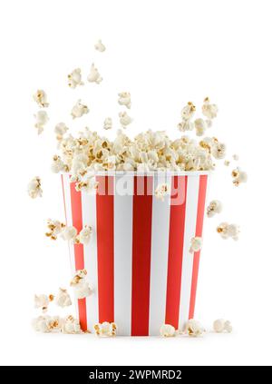 Pop-corn tombant d'un récipient rayé rouge et blanc, isolé sur fond blanc. Banque D'Images