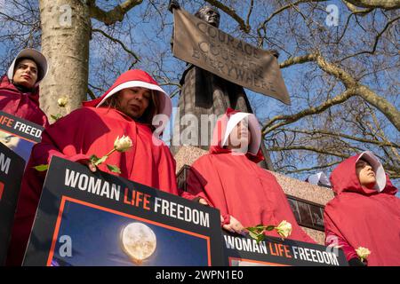 Londres, Royaume-Uni, 8 mars 2024, des femmes iraniennes vêtues de costumes de Handmaid Tale marchent de la place du Parlement à l'ambassade iranienne à Kensington. En passant par le centre de Londres, le cortège s'arrête à plusieurs sites célèbres, notamment Downing Street et Trafalgar Square. Le groupe des femmes espère attirer l'attention sur les violations des droits de l'homme en Iran. Crédit : James Willoughby Banque D'Images