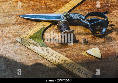 Ancien outil de mesure tailleur avec des ciseaux et de la craie sur le banc de travail tailleur Banque D'Images