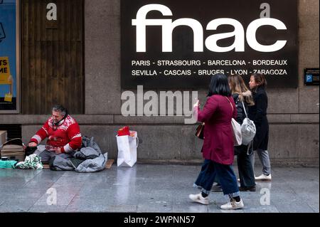 Madrid, Espagne. 08 mars 2024. Un sans-abri est vu à l'entrée du magasin Fnac de la chaîne multinationale française d'électronique et culturelle alors que des piétons le passent devant en Espagne. (Photo de Xavi Lopez/SOPA images/Sipa USA) crédit : Sipa USA/Alamy Live News Banque D'Images