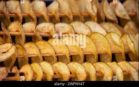 Pommes de terre frites, en spirale sur des bâtonnets de bois, en spirale. Vente de produits alimentaires sur le marché. Les aliments frits. L'alimentation de rue, une spirale de pommes de terre frites sur un bâton. Banque D'Images