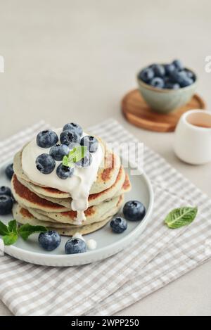 Assiette des crêpes aux myrtilles avec de la crème sure et du café en arrière-plan. Banque D'Images