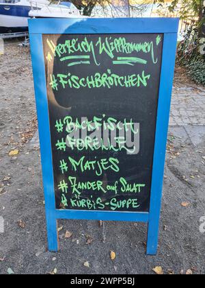 Un panneau publicitaire à Wannsee annonce des sandwichs de poisson, du poisson frit, de la truite, des matjes, de la perche de brochet sur une salade et de la soupe de citrouille à la main sur son panneau d'affichage Banque D'Images