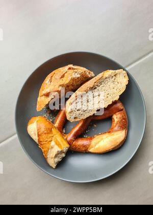 Les restes de pain et de produits de boulangerie tels que les bretzels et les bâtonnets de bretzel reposent sur une assiette grise Banque D'Images