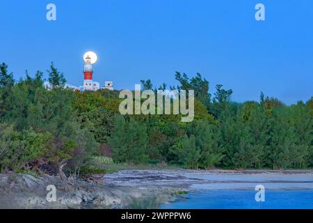 Full Wolf Moon Rising Behind Phare de David Clearwater Beach, Bermudes Banque D'Images