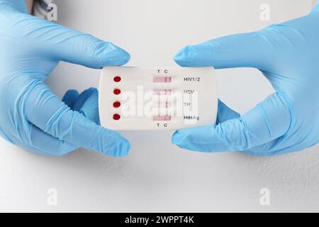 Docteur tenant le test express multi-infection jetable à table blanche, gros plan Banque D'Images