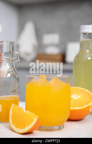 Savoureux kombucha en verre, bouteilles et orange fraîche sur table blanche Banque D'Images