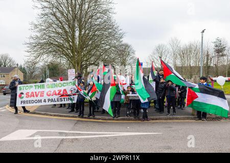 Bingley, Royaume-Uni. 08 MAR, 2024. Des manifestants rassemblés se tiennent devant les portes de l'école primaire de Cottingley Village. Histoire : les parents d’élèves de l’école primaire Cottingley Village ont sorti leurs enfants à 14h le 8 mars dans le cadre d’un effort de grève coordonné dans plusieurs écoles différentes à travers le Yorkshire pour la Palestine. Crédit Milo Chandler/Alamy Live News Banque D'Images