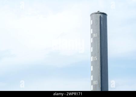 Jauge de niveau d'eau indiquant la profondeur de l'eau à un port sur une toile de fond d'un ciel nuageux bleu clair, fond d'espace de copie. Mesure de la profondeur d'un b Banque D'Images