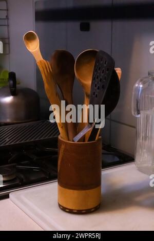 Beaucoup d'ustensiles de cuisine en bois brun et en plastique noir sur un vase en bois Banque D'Images