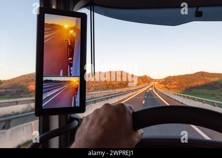 Vue depuis la position du conducteur d'un camion sur la route d'un lever de soleil vu par la caméra de vision arrière du véhicule. Banque D'Images